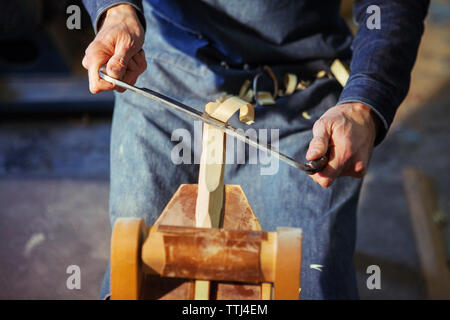 Mittelteil der Tischler rasieren Holz mit drawknife in Werkstatt Stockfoto