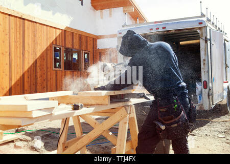 Arbeiter, der Holzdielen mit Kreissäge auf der Baustelle schneidet Stockfoto