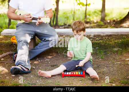 Vater und Sohn spielen mit musikalischen Spielzeug Instrumente auf Spielplatz Stockfoto