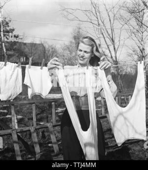 Die Wäsche in den 1940er Jahren. Eine Dame im Garten Aufhängen der Wäsche zu trocknen. Schweden 1947 Kristoffersson ref AB 10-5. Schweden 1951 Stockfoto