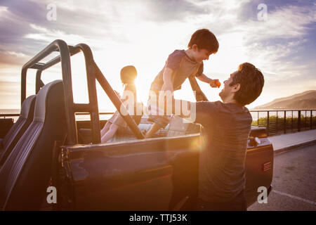 Mann anheben Junge aus Pick-up-Truck bei Sonnenuntergang Stockfoto