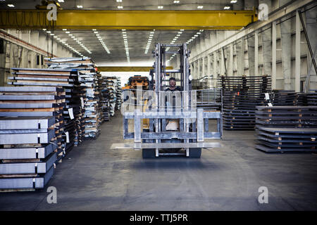 Arbeiter, der während der Arbeit Gabelstapler in der Metallindustrie fährt Stockfoto