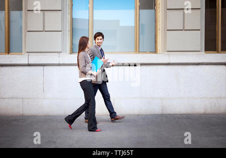 Geschäftsleute, die sich unterhalten, während sie auf Gehwegen laufen Stockfoto