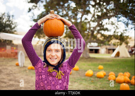 Portrait von Mädchen mit Kürbis auf dem Kopf in der Farm Stockfoto