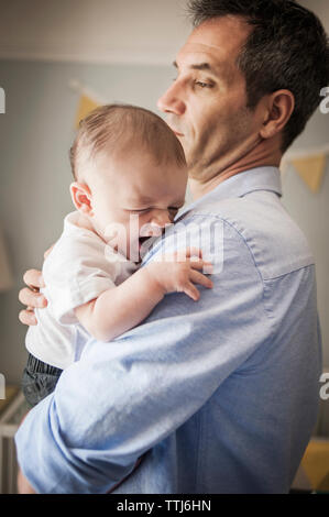 Mann, baby boy, während zu Hause stehend Stockfoto