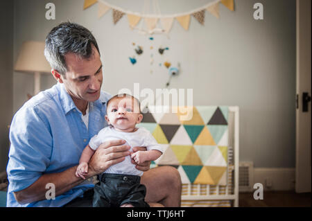 Der Mensch auf der Suche nach baby boy, während zu Hause sitzen Stockfoto
