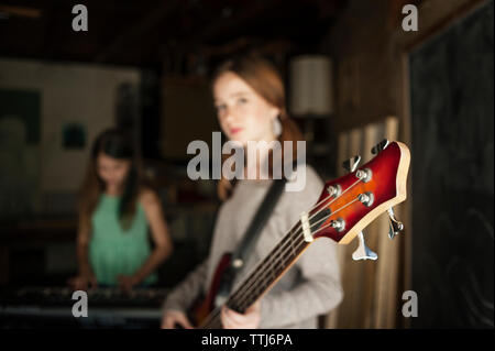 Mädchen mit Gitarre mit Freund im Hintergrund Stockfoto