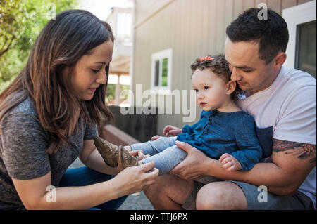 Vater mit Baby, während Mutter Unterstützung bei Schuhe Stockfoto