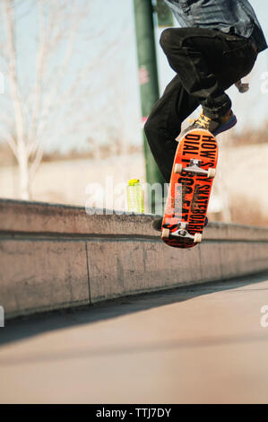 Niedrige Abschnitt des Menschen Durchführung Stunt mit Skateboard Stockfoto