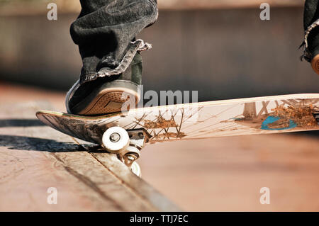 Niedrige Abschnitt des Menschen Durchführung Stunt mit Skateboard auf Sport Rampe Stockfoto