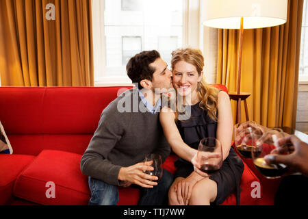 Glückliche Menschen küssen Freundin Holding wineglass Stockfoto