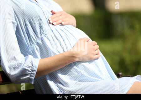 Schwangere Frau auf Stuhl in Park Stockfoto