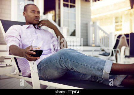 Nachdenklicher Mann, Wineglass sitzend auf Liegestuhl Stockfoto