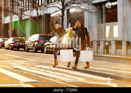 Freunde Anheben der Arme beim Überqueren der Straße Stockfoto