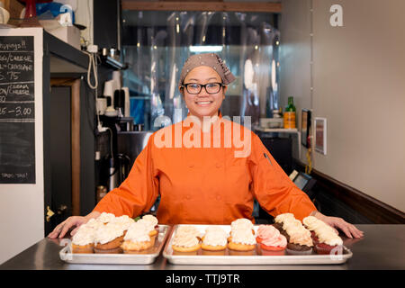 Porträt der Frau, die mit Cupcakes bei Store Stockfoto