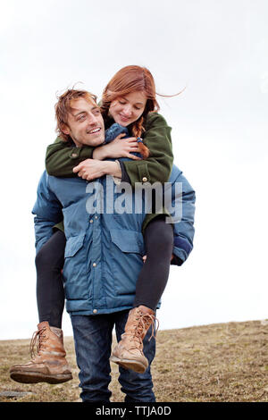 Mann huckepack Freundin beim Gehen auf gegen den klaren Himmel Stockfoto