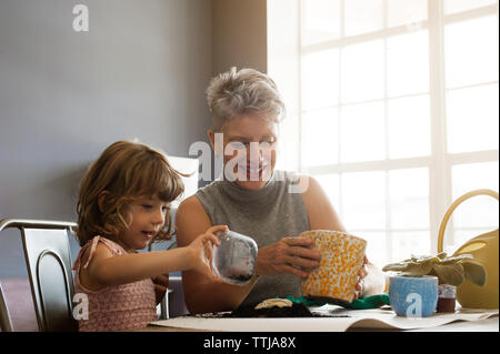 Glückliche Frau mit Enkelin pflanzen Bäumchen im Topf zu Hause Stockfoto