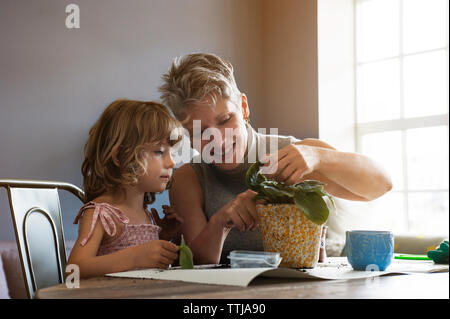 Mädchen mit Großmutter plating Bäumchen im Topf zu Hause Stockfoto