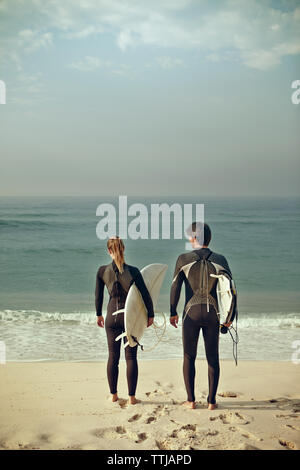 Ansicht der Rückseite des Paares, die surfbretter beim Stehen am Ufer Stockfoto