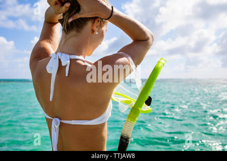 Frau mit Schnorchel einstellen Haar beim Stehen in der Meer Stockfoto