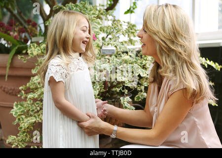 Glückliche Mutter halten sich an den Händen, während im Gespräch mit Tochter Stockfoto