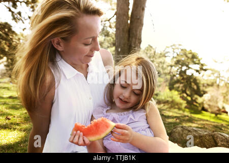 Mutter auf der Suche nach Girl holding Wassermelone im Hinterhof Stockfoto