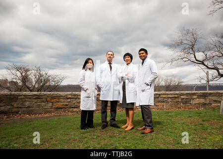 Portrait von Ärzten stehen auf Feld gegen bewölkter Himmel Stockfoto