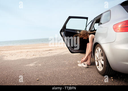 Frau Schuhe beim Sitzen im Auto am Strand Stockfoto