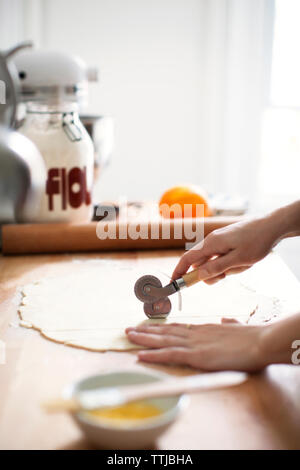 7/8 Bild der Frau schneiden Teig durch Cutter für die Zubereitung von Kuchen Stockfoto