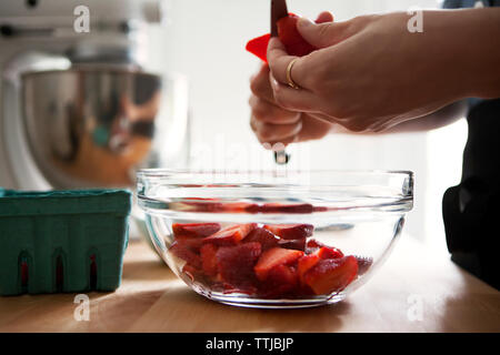 Zugeschnittenes Bild der Hände schneiden Erdbeeren Stockfoto