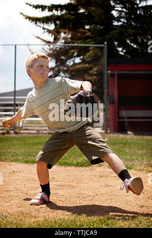 Junge werfen Baseball am Feld Stockfoto