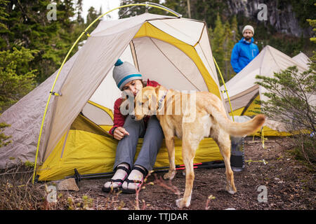 Frau mit Hund sitzen im Zelt beim Mann am Feld Stockfoto