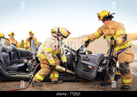 Feuerwehrmänner schneiden Auto während der Praxis Bohren Stockfoto