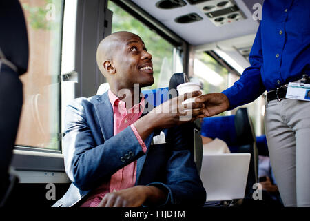 Glückliche Menschen, die trinken aus der Führung während im Bus sitzen Stockfoto