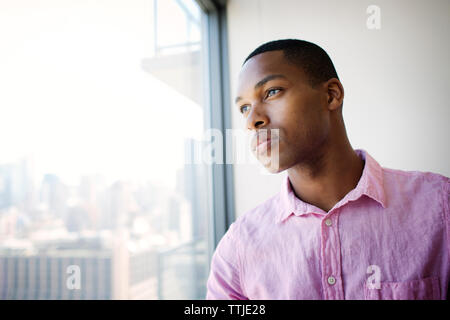 Nachdenklich Geschäftsmann auf der Suche über office Fenster Stockfoto