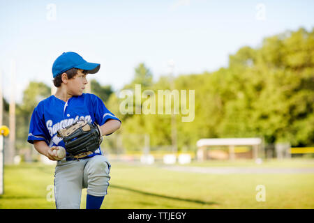 Junge spielt Baseball auf Feld Stockfoto