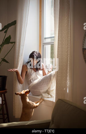 Frau mit Hund sitzend auf Fensterbank Stockfoto