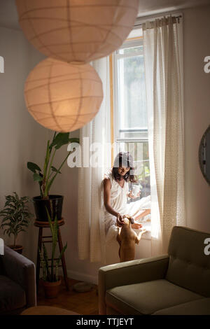 Frau Hund streicheln, während auf der Fensterbank zu Hause sitzen Stockfoto