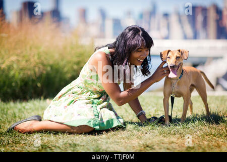 Frau spielen mit Hund beim Sitzen auf dem Feld Stockfoto