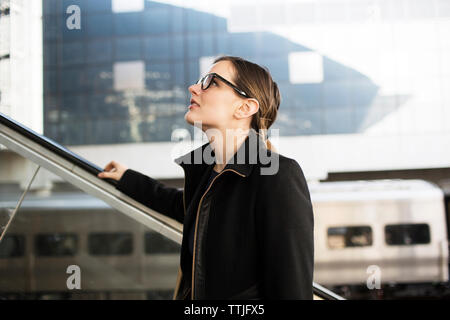 Frau suchen, um sich beim Stehen auf Rolltreppe in der U-Bahn Station Stockfoto