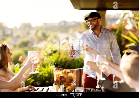 Freunde mit weingläser am Esstisch auf der Veranda Stockfoto