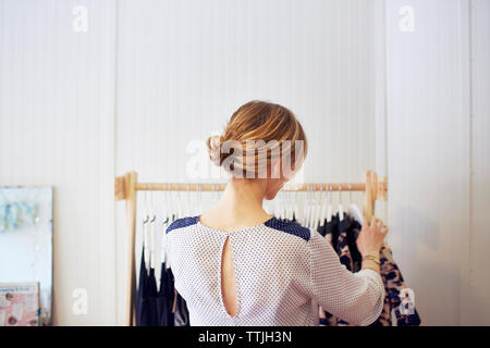 Ansicht der Rückseite Frau Anordnen von Kleidung im Rack Stockfoto