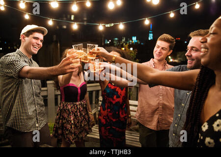 Fröhliche Freunde toasten Getränke bei Party Stockfoto