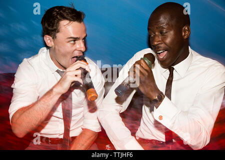 Freunde singen Karaoke in Nachtclub Stockfoto