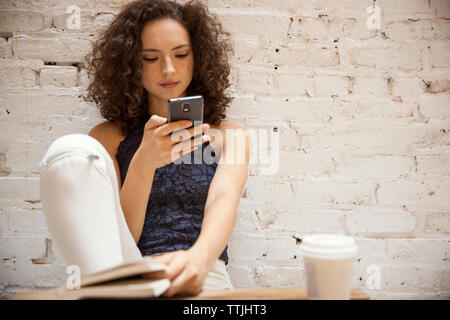 Frau mit Smart Phone und Straßencafé sitzen Stockfoto