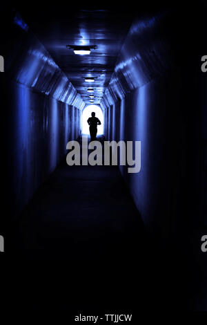 Mann in Tunnel in Richtung Licht läuft auf der Suche nach einem bestimmten Ziel und Leistung Stockfoto