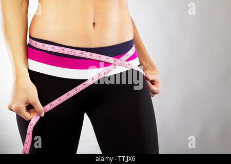 Mittelteil der Frau messen Taille gegen grauer Hintergrund Stockfoto