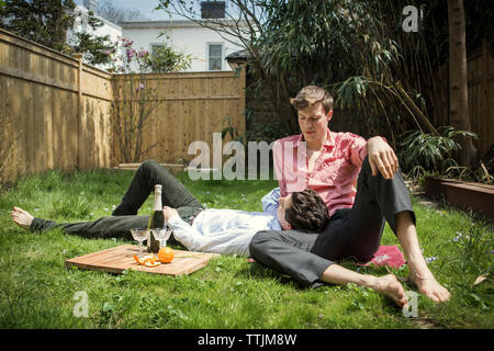 Homosexuelles Paar entspannend auf Feld im Hinterhof Stockfoto