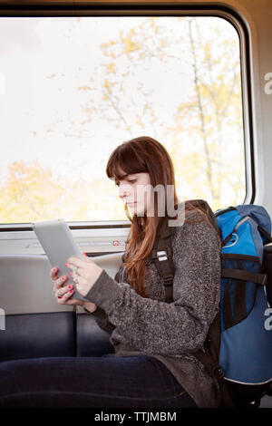 Frau mit Tablet Computer während des Standorts in Zug Stockfoto
