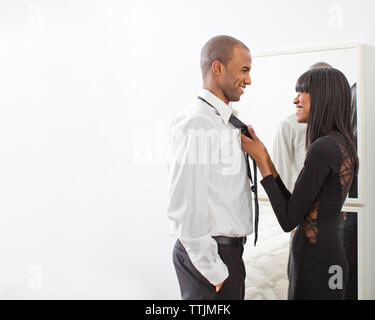Seitenansicht der Frau die Krawatte des Mannes während zu Hause stehend Stockfoto